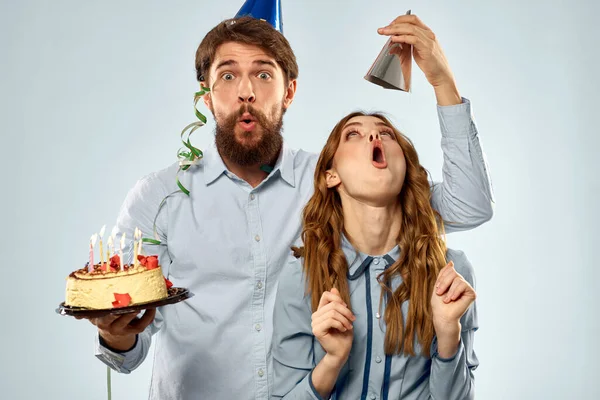 Urodzinowy mężczyzna kobieta w imprezowy kapelusz na błękitny tło i tort z świeca — Zdjęcie stockowe