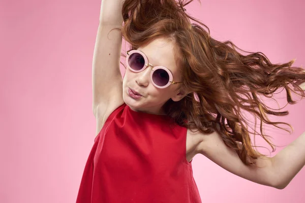 Κορίτσι με σγουρά μαλλιά σκούρα στρογγυλά γυαλιά διασκέδαση κόκκινο φόρεμα ροζ φόντο — Φωτογραφία Αρχείου