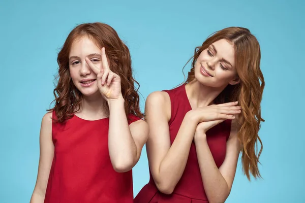 Famille maman et fille câlin robes rouges communication émotions fond bleu — Photo