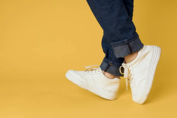feet jeans fashion shoes white sneakers yellow background