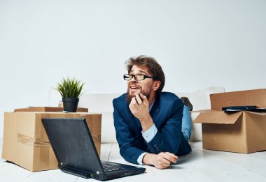 Bir adam dizüstü bilgisayar kutularının önünde bavullarını boşaltan profesyonel bir işadamıyla yatıyor.