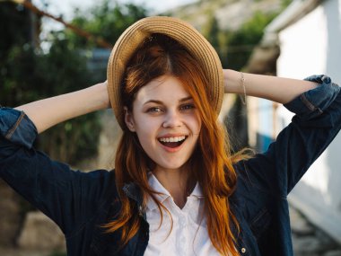 Kırsal kesimde kırmızı saçlı, şapkalı, mutlu bir kadın. 