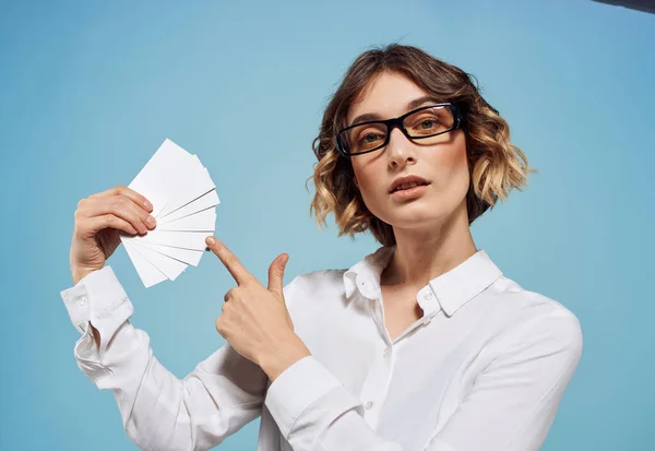 Egy nő szemüvegben, egy köteg névjegykártyával a kezében, kék alapon. — Stock Fotó