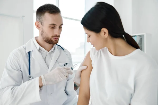 Doctor with a stethoscope injections in the patients shoulder coronavirus epidemic infection —  Fotos de Stock