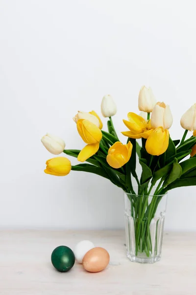 花瓶里的一束黄色郁金香和教堂传统的复活节彩蛋 — 图库照片