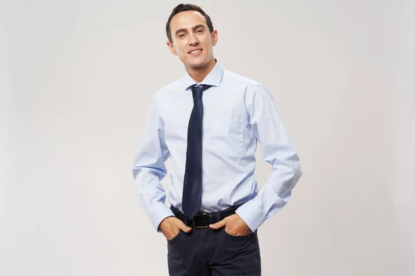 Üzletember egy klasszikus öltöny egy könnyű háttér tartja a kezét a zsebében — Stock Fotó