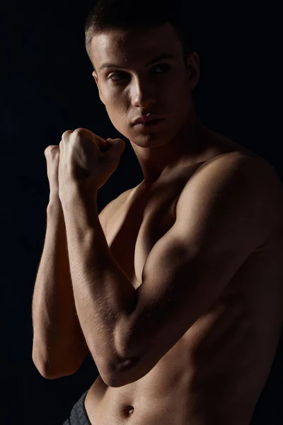 Sportovní chlap s čerpané paže svaly na černém pozadí při pohledu na straně close-up portrét — Stock fotografie