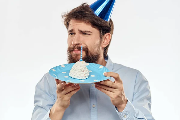 Un hombre con barba sostiene un pastel en su mano sobre un fondo claro cumpleaños — Foto de Stock