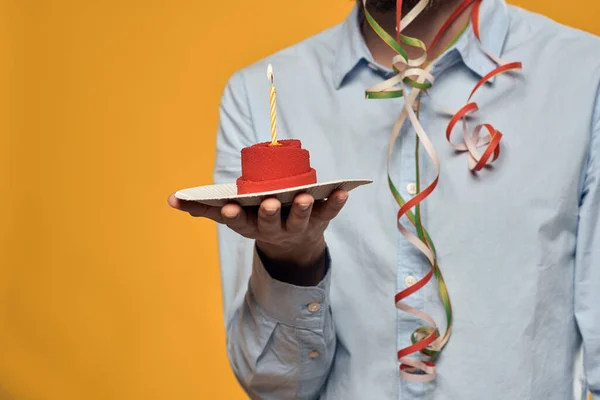 Um homem segurando um bolo em um prato e uma vela de cima fundo isolado — Fotografia de Stock