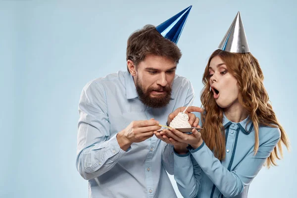 Homem alegre e mulher com bolo em uma placa de festa corporativa fundo azul — Fotografia de Stock