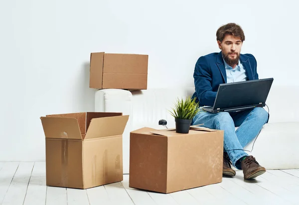 Manager sitzt mit Laptop auf der Couch und arbeitet professionelle Boxen mit Dingen — Stockfoto