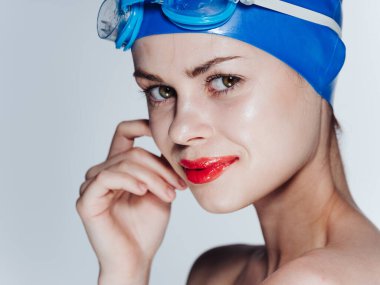 Mavi yüzme şapkası ve açık arkaplanda gözlüklü güzel bir kadının portresi.