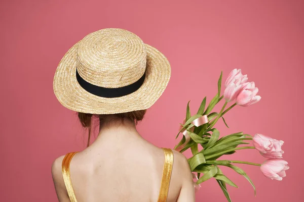 Mulher em um buquê de chapéu de flores em um vestido visão traseira fundo rosa — Fotografia de Stock