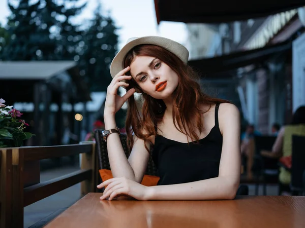 街上一家咖啡馆里的浪漫女人和艳丽的妆容注视着一顶白帽 — 图库照片
