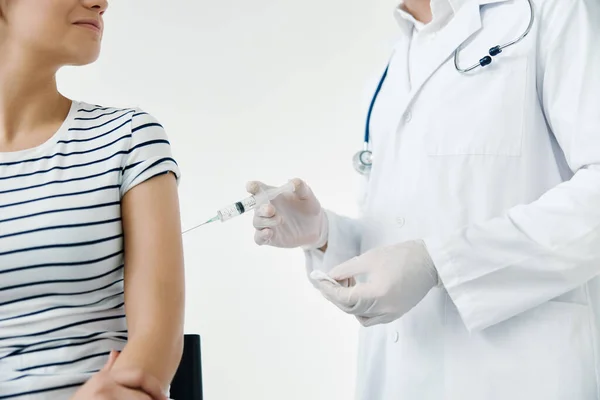 En läkare i vit rock ger en injektion i axeln på en kvinnlig patient vaccination — Stockfoto