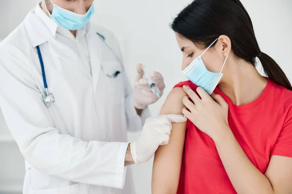 A doctor in a white coat makes an injection in the patients shoulder from coronavirus —  Fotos de Stock