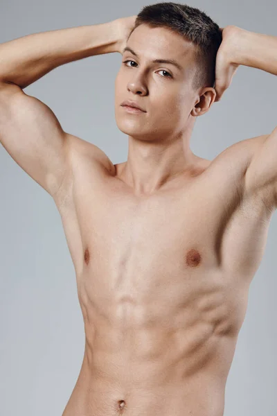 Athlete with pumped muscles holds his hands behind his head on a gray background model — 스톡 사진