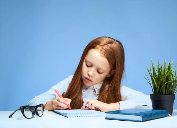 Menina de cabelos vermelhos fazendo lição de casa na escola de mesa educação disciplina — Fotografia de Stock