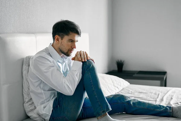 lonely man sitting on sofa indoors puzzled look