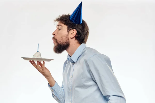 Un hombre con barba sostiene un pastel en su mano sobre un fondo claro cumpleaños — Foto de Stock