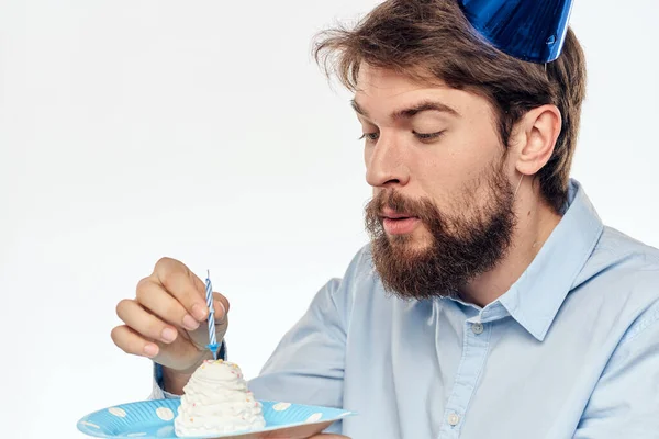 Mężczyzna z talerzem ciasta i w niebieskiej koszuli na jasnym tle urodziny impreza korporacyjna czapka — Zdjęcie stockowe