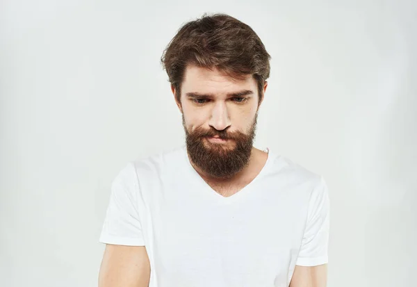 Homme barbu en T-shirt blanc look perplexe regard triste visage recadré — Photo