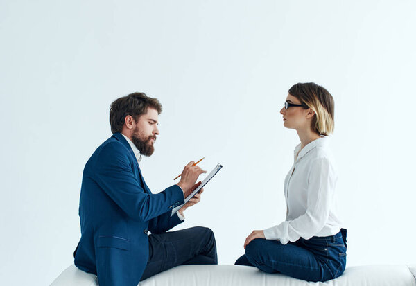 Woman and man are sitting on the couch in suits psychology papers