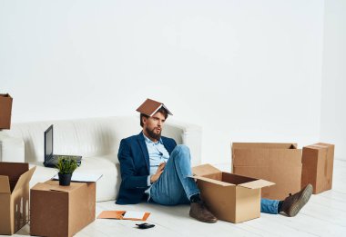 Bir adam, resmi bir işadamının duygularının açıldığı bir kutunun zemininde oturuyor.