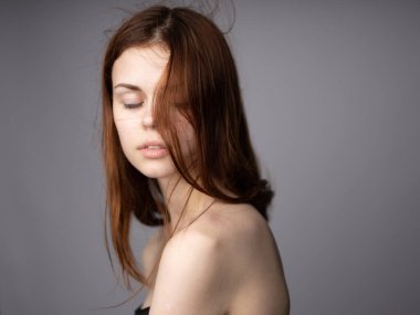 Gri arka planı olan, kızıl saçlı, çekici bir kadın.