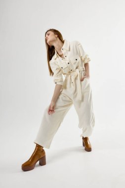 Modern tarz giyinmiş, hafif arka plan pozu veren kadın.