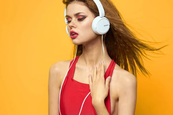 Jolie femme en t-shirt rouge casque musique fond jaune — Photo