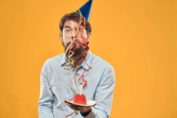 Un hombre con un pastel en un plato sobre un fondo amarillo — Foto de Stock