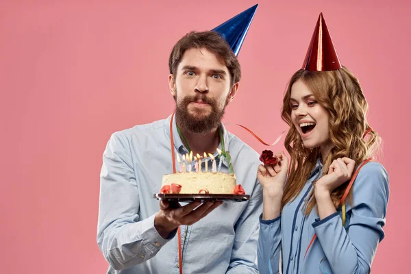 Festa homem e mulher com bolo no fundo rosa aniversário corporativo — Fotografia de Stock