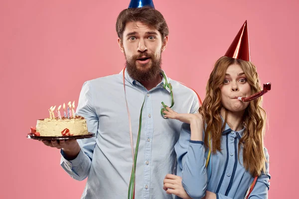 Party man and woman with cake on pink background corporate birthday