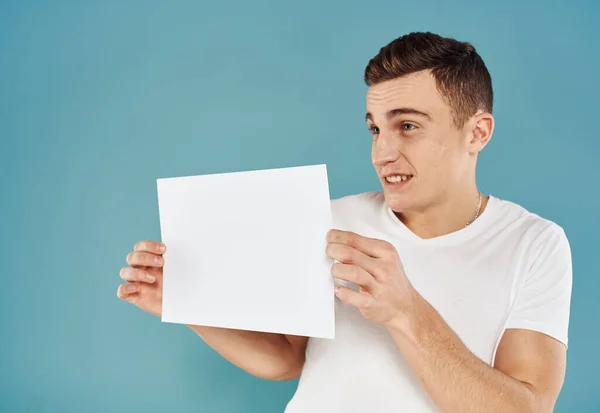 Cute man with white sheet of paper on blue background cropped view mockup