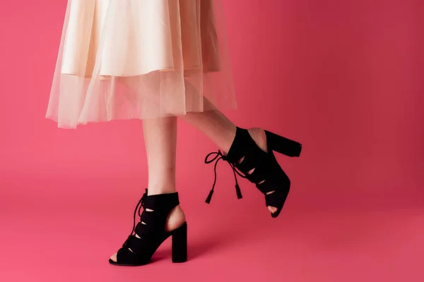 Female feet black fashionable heels shoes charm pink background — Stock Photo, Image