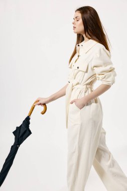 Güzel kadın beyaz tulum şemsiyesi ellerinde kapalı gözler açık moda arka planı