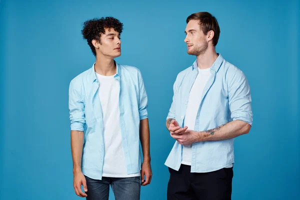 Ragazzi in camicie identiche e una t-shirt su uno sfondo blu amici gesticolare con le mani — Foto Stock