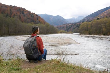Gezgin, nehrin kıyısında, dağların arkasında oturur.