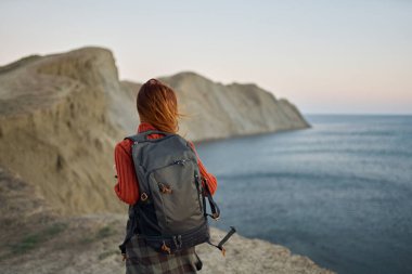 Sırt çantalı romantik gezgin doğada gün batımında ve arka planda deniz