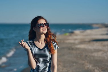 Tişörtlü ve gözlüklü bir kadın portresi. Deniz kenarındaki dağlarda.