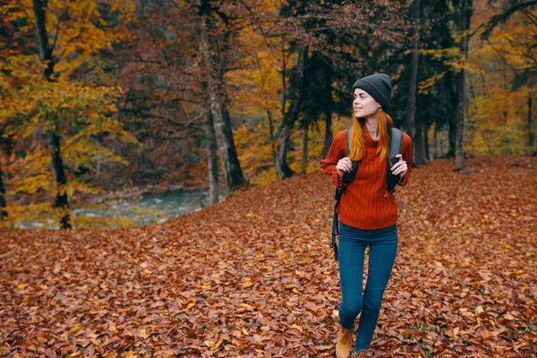 Reisende mit Rucksack im Herbstwald und Mütze Pullover Jeans umgestürzte Blätter Seebäume — Stockfoto