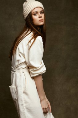 fashionable woman in a hat and overalls on a dark background side view