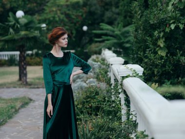 Yeşil elbiseli bir kadın açık havada romantizm içinde yürüyor.