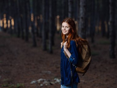 Sırt çantalı bir kadın turist ormanda doğa yürüyüşü yapıyor.