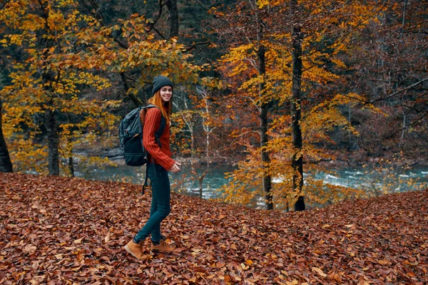 Un viaggiatore con uno zaino passeggiate nel parco nella natura vicino al fiume in autunno — Foto Stock