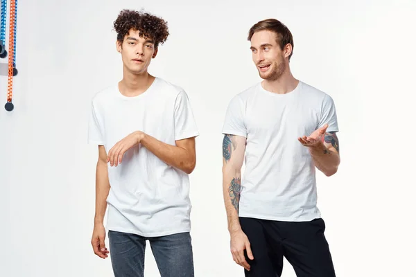 Twee vrolijke vrienden in witte t-shirts emoties positief licht achtergrond — Stockfoto