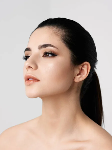 Pretty woman with makeup on face bared shoulders close-up side view — Stockfoto