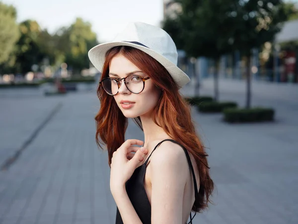 Donna attraente che cammina per strada indossando cappello e occhiali — Foto Stock