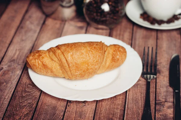 Croissant em um prato na mesa utensílios de cozinha café da manhã refeição — Fotografia de Stock